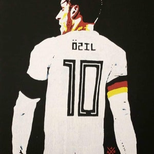 May include: A white soccer jersey with black and yellow accents. The jersey has the number "10" and the name "Özil" printed on the back.