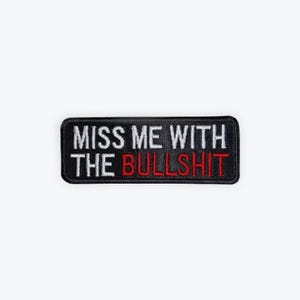 May include: A rectangular black patch with white embroidered text that reads "MISS ME WITH THE BULLSHIT". The word "BULLSHIT" is embroidered in red. The patch is likely designed to be sewn or ironed onto clothing or accessories.