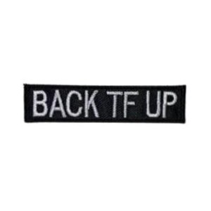 May include: A rectangular black embroidered patch featuring the white text BACK TF UP in a bold, sans-serif font. The patch has a clean, stitched border and a flat, textured surface, designed for application onto fabric garments or accessories.