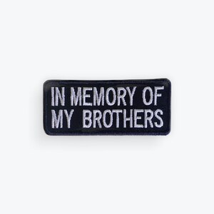 May include: A rectangular, navy blue patch with white embroidered text. The text reads "IN MEMORY OF MY BROTHERS". The patch has a black border and is set against a white background.