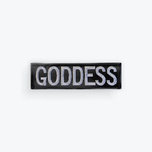 May include: Black rectangular patch with the word "GODDESS" embroidered in silver thread. The patch has a shiny, reflective surface and is set against a white background.