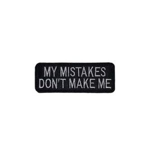 May include: Black rectangular patch with white text that reads "MY MISTAKES DON'T MAKE ME". The patch has a black border and is likely made of fabric. The text is in a sans-serif font.