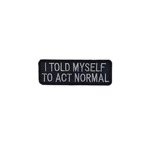 May include: A rectangular black embroidered patch with white stitched lettering that reads I TOLD MYSELF TO ACT NORMAL. The patch features a clean, bold font and a finished border, designed for application onto fabric surfaces as a decorative accessory.