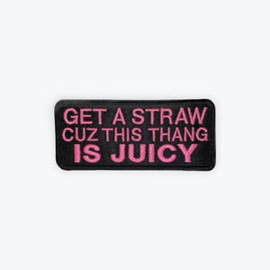 May include: Black rectangular patch with the text "GET A STRAW CUZ THIS THANG IS JUICY" embroidered in pink. The patch has a black border and is set against a white background.