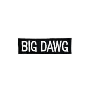 May include: A black rectangular patch with the white text "BIG DAWG" embroidered on it. The patch is centered on a white background. The letters are in a bold, sans-serif font.