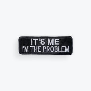 May include: A black rectangular patch with white embroidered text that reads "IT'S ME I'M THE PROBLEM". The patch is centered on a white background. The patch is likely for clothing or accessories.