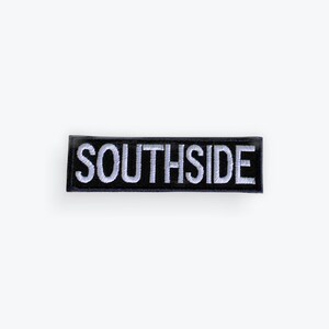 May include: A rectangular black patch with the word "SOUTHSIDE" embroidered in white block letters. The patch has a black border and is likely designed to be sewn or ironed onto clothing or accessories.