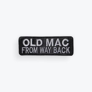 May include: Black rectangular patch with white embroidered text that reads "OLD MAC FROM WAY BACK". The patch has a black border and is likely designed to be sewn or ironed onto clothing or accessories.