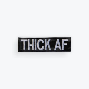 May include: Black rectangular patch with the embroidered text "THICK AF" in silver thread. The patch is centered on a white background, showcasing the bold statement.