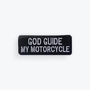 May include: Black rectangular patch with the embroidered text "GOD GUIDE MY MOTORCYCLE" in white. The patch has a rounded border and is likely designed to be sewn onto clothing or accessories.