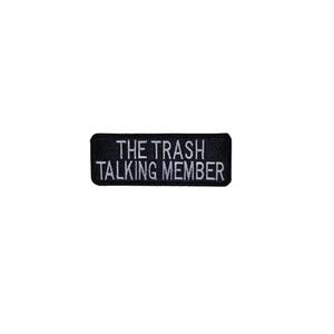 May include: A black rectangular patch with white embroidered text that reads "THE TRASH TALKING MEMBER". The patch is likely designed to be sewn or ironed onto clothing or accessories.