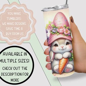 May include: A white tumbler with a pink and white bunny wearing a pink hat with flowers and holding a carrot. The bunny is surrounded by a floral design. The tumbler is available in multiple sizes.