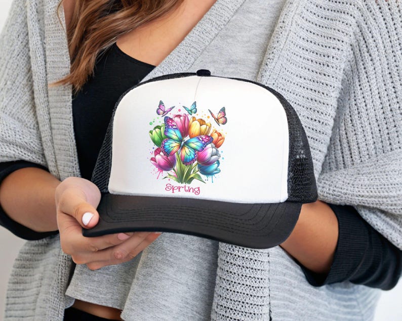 May include: A black and white trucker hat with a white front panel featuring a colorful watercolor design of tulips and butterflies. The text "spring" is printed below the design.