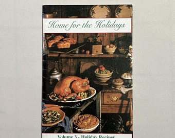 May include: A cookbook titled "Home for the Holidays, Volume 3 - Holiday Recipes" features a festive image. The cover showcases a roasted turkey, side dishes, and baked goods, suggesting a holiday meal. The background includes a rustic kitchen setting.