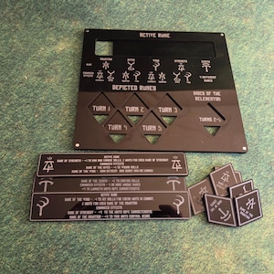 May include: A black game board with etched white symbols and text, including "ACTIVE RUNE" and "DEPICTED RUNES." Several rectangular and square game pieces with similar designs are also present. The game pieces are on a green surface.