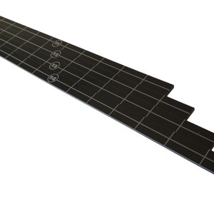 May include: Black guitar fretboard with white grid lines and numbered circles. The fretboard is layered, with the top layer showing the numbers 12, 13, and 14. The product is designed for guitarists and musicians.
