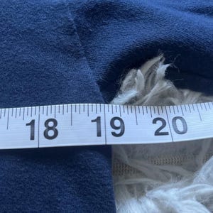 K&ouml;nnte beinhalten: Ein marineblauer Stoff wird mit einem wei&szlig;en Ma&szlig;band gemessen. Das Band zeigt Messungen von 45,7 bis 50,8 cm. Der Stoff ist strukturiert und scheint ein Kleidungsst&uuml;ck zu sein.