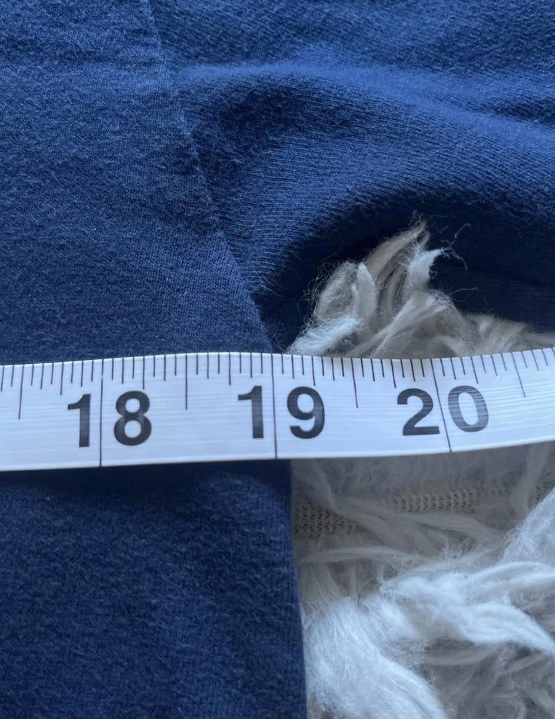 K&ouml;nnte beinhalten: Ein marineblauer Stoff wird mit einem wei&szlig;en Ma&szlig;band gemessen. Das Band zeigt Messungen von 45,7 bis 50,8 cm. Der Stoff ist strukturiert und scheint ein Kleidungsst&uuml;ck zu sein.