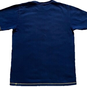 K&ouml;nnte beinhalten: Marineblaues T-Shirt mit Rundhalsausschnitt und kurzen &Auml;rmeln. Das Shirt hat hellfarbene N&auml;hte entlang der N&auml;hte. Der Stoff scheint ein weiches, l&auml;ssiges Material zu sein. Dieses Basic-T-Shirt ist f&uuml;r den Alltag geeignet.