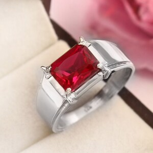 May include: A silver ring with a large, rectangular, red gemstone.
