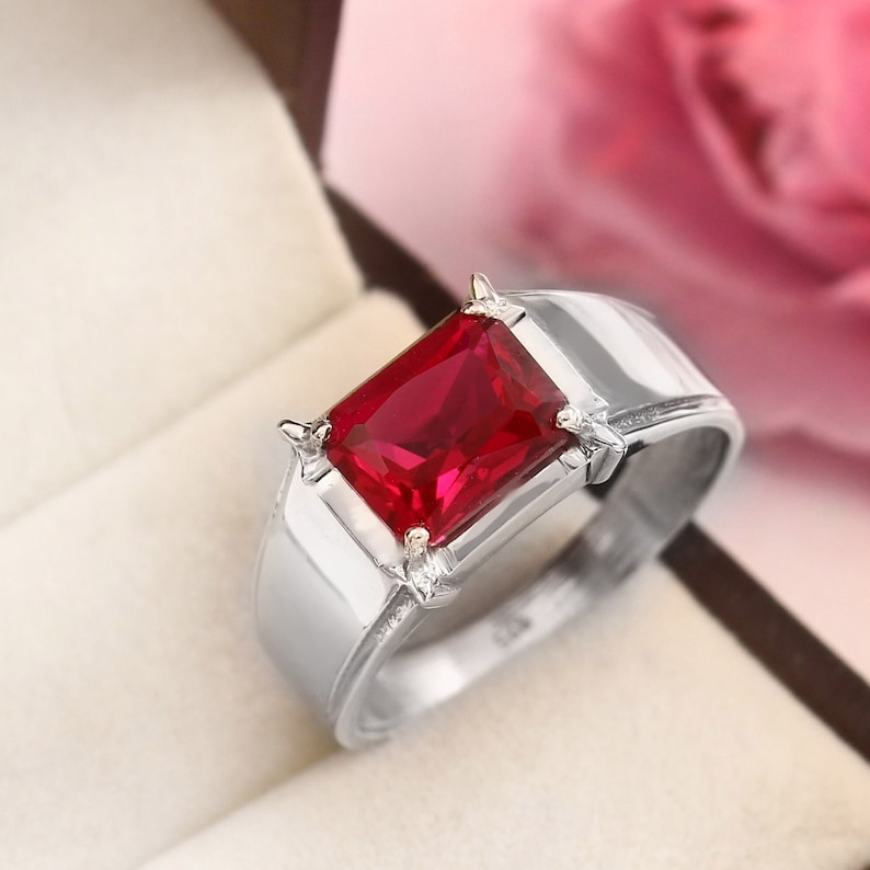 May include: A silver ring with a large, rectangular, red gemstone.