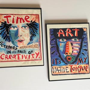 May include: Two framed art prints. One features a blue-toned face with the word "Time" above and the phrase "Becomes Meaningless in the Face of Creativity." The other print displays a blue face with the word "Art" and the phrase "It's My Native Tongue."