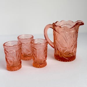 Vintage small scale shot glasses and pitcher peach colored depressionware with tropical design