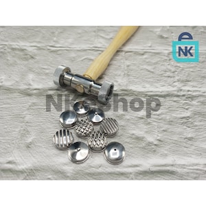 May include: A metal hammer with a wooden handle and a set of interchangeable metal heads. The heads have various textured patterns, including lines, dots, and diamond shapes. The hammer and heads are silver in color.