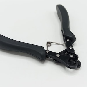 May include: Black wire crimping tool with black handles and a silver spring. The tool is designed for crimping wires and has a compact design. The handles are ergonomically shaped for a comfortable grip.