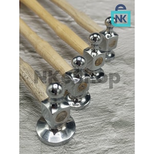 May include: A set of four metal hammers with wooden handles. The hammer heads are square with a circular top and a circular base. The handles are light brown. The hammers are arranged diagonally, with the heads facing the viewer.