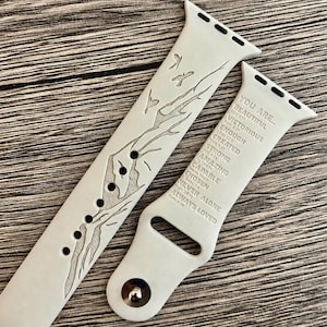 May include: A white silicone watch band featuring an engraved mountain landscape with birds on one side and the text YOU ARE... BEAUTIFUL, VICTORIOUS, ENOUGH, CREATED, STRONG, AMAZING, CAPABLE, CHOSEN, NEVER ALONE, ALWAYS LOVED with scripture references.