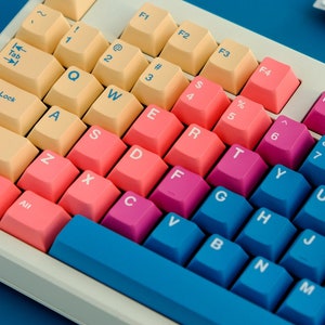 May include: A white keyboard with pastel colored keys. The keys are labeled with letters, numbers, and symbols. The keyboard has a blue space bar and a blue row of keys at the bottom.