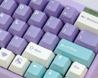 May include: A purple mechanical keyboard with white and blue keycaps. The keyboard has a variety of keys, including letters, numbers, symbols, and arrow keys. The keyboard also has a backspace key, an enter key, a shift key, and a delete key. The keyboard is on a white surface.