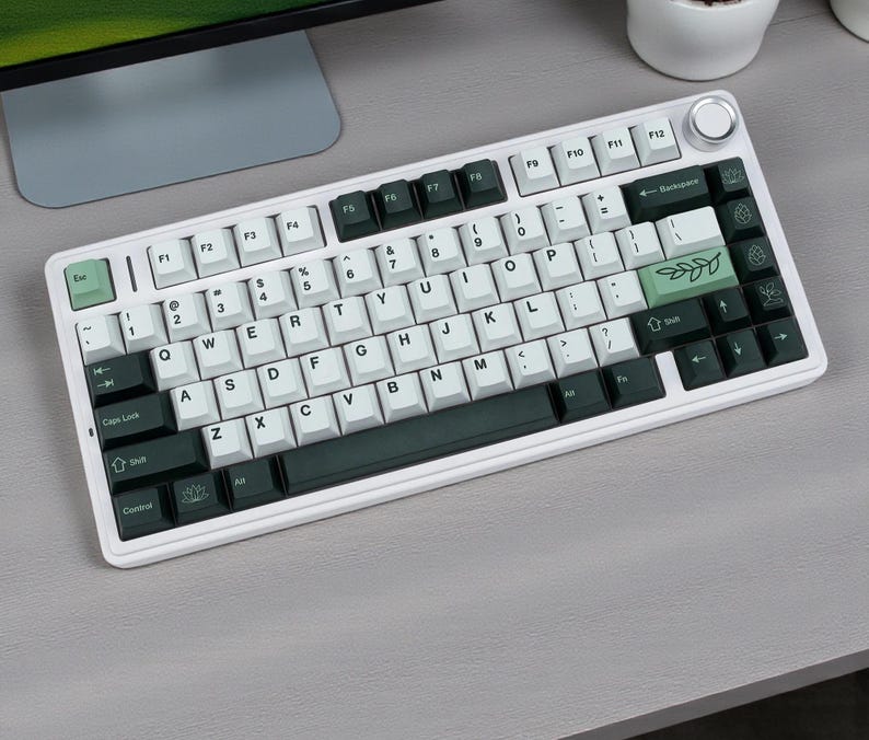 May include: A white mechanical keyboard with a variety of key colors, including white, black, and green. The keyboard has a volume knob and a layout with function keys. The keycaps feature standard letters, numbers, and symbols.