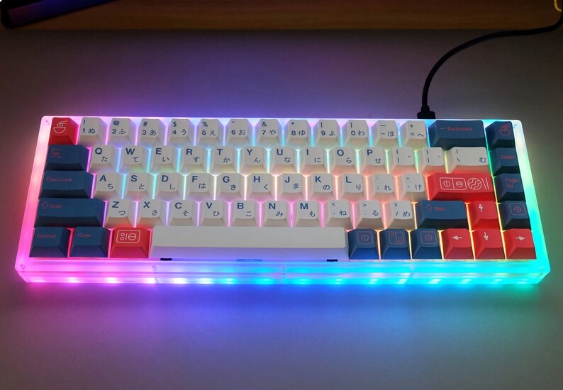May include: A white mechanical keyboard with a clear case and rainbow LED backlighting. The keyboard has Japanese characters on the keys and a white space bar.