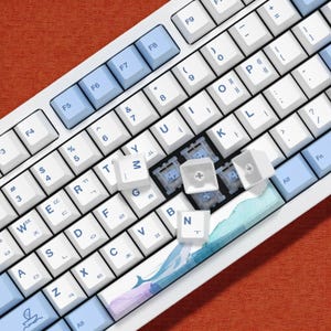 May include: A white mechanical keyboard with light blue and white keycaps. The keyboard has a variety of keys, including function keys, number keys, and letter keys. Some keycaps are removed, revealing the switches.