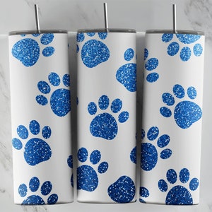 May include: Three white tumblers with blue glitter paw print designs. The tumblers are stainless steel and have a straw hole.