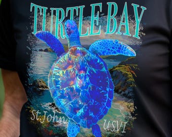 May include: Black t-shirt featuring a vibrant blue sea turtle design with the text "TURTLE BAY" in teal. The shirt also includes "St. John USVI" in white text, creating a tropical theme.