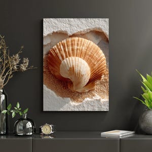 May include: A framed artwork featuring two seashells in shades of brown and white, set against a textured white and sandy background. The larger shell is open, revealing the smaller shell within. The artwork evokes a coastal theme.
