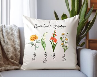 Puede incluir: Almohada blanca con el texto "Grandma's Garden" y cuatro ilustraciones florales con los nombres "Junko", "Johanka", "Vilko" y "Eilko" escritos debajo de cada flor.