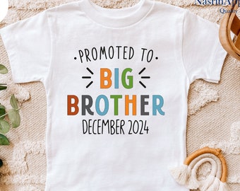 May include: White t-shirt with the text "Promoted to Big Brother December 2024" in colorful letters.