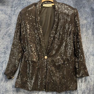 May include: A black sequined blazer with a notched collar and a single button closure. The blazer has long sleeves and two front pockets. The label reads "French Collection".