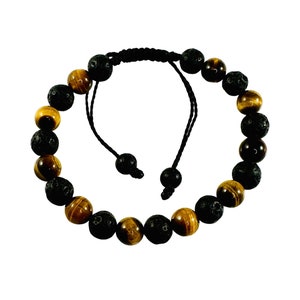 May include: A black and brown beaded bracelet with alternating tiger's eye and lava rock beads. The bracelet is adjustable with a sliding knot.