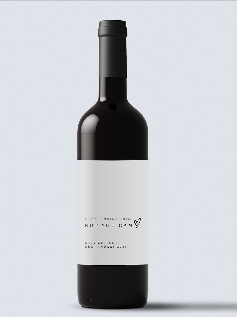 May include: A dark red wine bottle with a black top and a white label. The label reads "I CAN'T DRINK THIS, BUT YOU CAN" with a heart symbol, and "BABY CHILCOTT DUE JANUARY 2023".