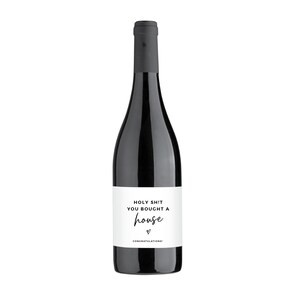 Puede incluir: Una botella de vino tinto con una etiqueta blanca que dice "Holy Shit You Bought A House" con un coraz&oacute;n y la palabra "Congratulations!"