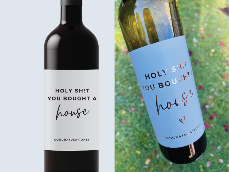 Puede incluir: Dos botellas de vino con etiquetas que dicen "HOLY SH!T YOU BOUGHT A house" en texto blanco y negro con una "house" en cursiva en l&aacute;mina dorada. La etiqueta de la botella de la izquierda es blanca y la etiqueta de la botella de la derecha es azul claro. Ambas etiquetas tienen el texto "CONGRATULATIONS!" en la parte inferior.