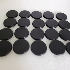 May include: A set of 18 black round plastic bases for miniature figures. The bases are arranged in a grid pattern.