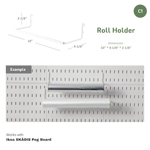 May include: White metal roll holder for a peg board. The holder is 10 inches long, 4-1/8 inches tall, and 2-1/8 inches deep. It is shown holding a roll of plastic wrap and a roll of aluminum foil. The text "Roll Holder" and "Dimension: 10" * 4-1/8" * 2-1/8"" is visible in the image. The text "Works with Ikea SKÅDIS Peg Board" is also visible in the image.