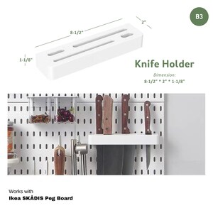 May include: White plastic knife holder with three slots for knives. The holder is 8 1/2 inches long, 2 inches wide, and 1 1/8 inches tall. It is designed to fit on a pegboard.