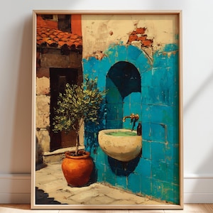 May include: A framed wall art print depicting a Mediterranean scene with a bright blue tiled wall, a stone basin fountain with a brass faucet, and a small green tree in a terracotta pot set against a rustic building with a red tiled roof.